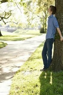 一个女孩坐在树下的看书的侧面或者背面的图片